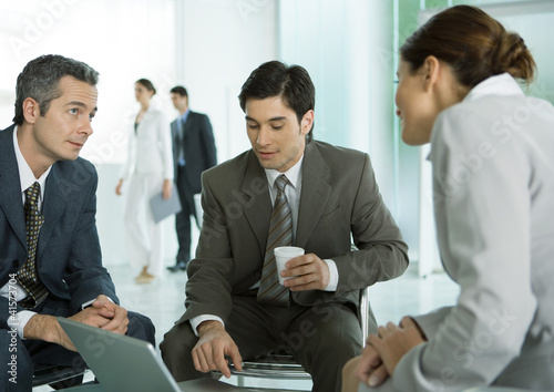 Photo: Business associates sitting in lobby having informal meeting Business associates sitting in lobby having informal meeting