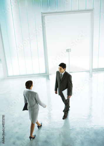Photo: Woman walking to meet businessman in lobby Woman walking to meet businessman in lobby