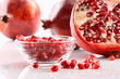 Photo: Ripe pomegranates and glass bowl of seeds on white Ripe pomegranates and glass bowl of seeds on white