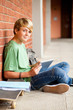 male high school teen student using tablet computer in school