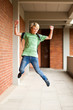 happy male high school student jumping up in school
