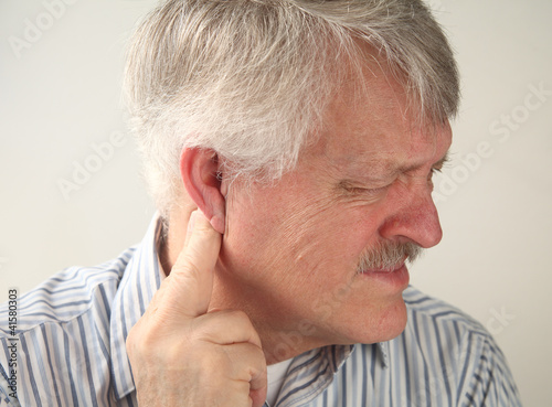 Photo: senior man suffers from pressure behind his ear senior man suffers from pressure behind his ear