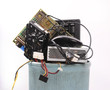 different computer parts and phone in trash can