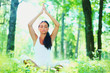 Young woman doing yoga exercise in green park