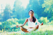 Foto: Young woman doing yoga exercise in green park Young woman doing yoga exercise in green park