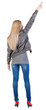 Back view of young blonde woman pointing at wall .