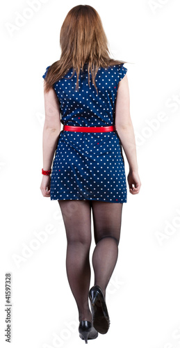 Photo: back view of going brunette woman in blue dress. back view of going brunette woman in blue dress.