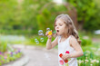 Cute curly girl  blowing  soap bubbles