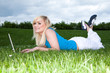 Girl lying on the grass working on a laptop