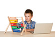 Kind mit Notebook und Abakus am Schreibtisch