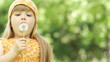 Little girl turned around and blowing on a dandelion