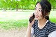 attractive asian woman talking by cellphone in the park