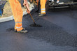 Photo: Roadworks worker with shovel and paving machine Roadworks worker with shovel and paving machine