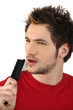 young man holding hairbrush as makeshift microphone