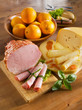 Breakfast arrangement with ham, cheese, loaf and oranges on a ki