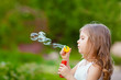 Cute curly girl  blowing  soap bubbles