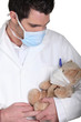 Doctor nursing a sick teddy bear wearing a mask