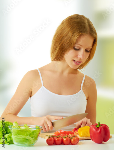 Photo: young woman, a housewife preparing dinner vegetable salad in the young woman, a housewife preparing dinner vegetable salad in the
