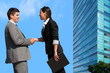 Business couple shaking hands over deal outdoors.