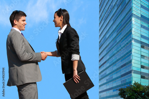 Photo: Business couple shaking hands over deal outdoors. Business couple shaking hands over deal outdoors.