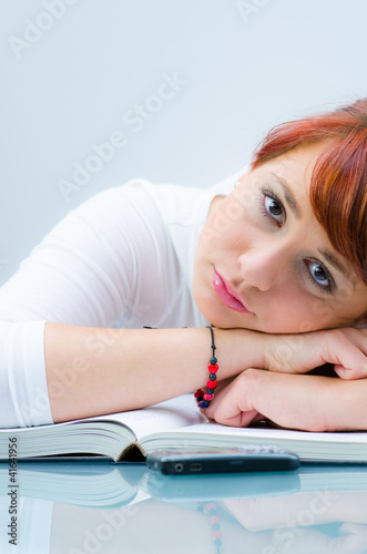 Photo: schülerin hängt lustlos über ihrem buch schülerin hängt lustlos über ihrem buch