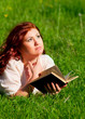 redhead beautiful girl reading a book in nature