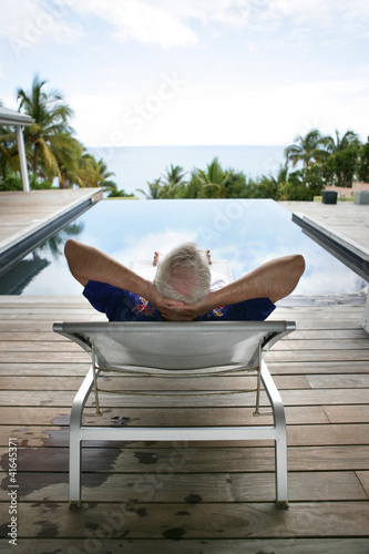 Photo: Senior man relaxing poolside Senior man relaxing poolside