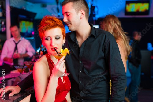 Foto: Young couple in bar or club drinking cocktails Young couple in bar or club drinking cocktails