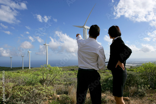 Photo: Business couple standing in a field of wind turbines Business couple standing in a field of wind turbines