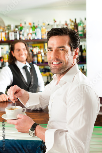 Photo: Barista mit Gast in seinem Cafe oder Coffeeshop Barista mit Gast in seinem Cafe oder Coffeeshop