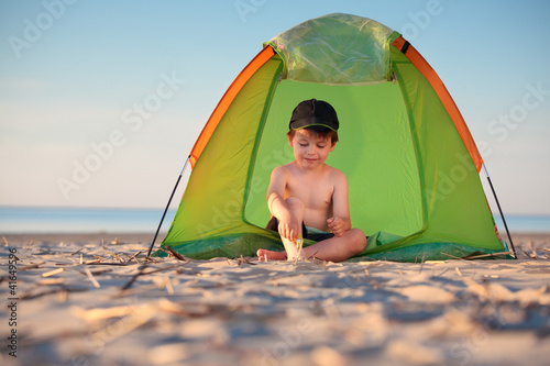 Photo: Little boy playing in his tent on the beach Little boy playing in his tent on the beach