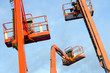 Orange construction crane baskets against blue sky