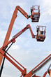 Orange construction crane baskets against blue sky