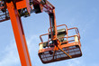 Orange construction crane baskets against blue sky