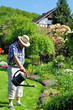 Senior gießt die Gartenblumen