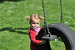 Mädchen steht an einer Schaukel auf dem Spielplatz