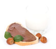 Chocolate spread container with a buttered toast, nuts and milk