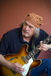 Mature guitarist with sunburst hollow body guitar and bandana Mature guitarist with sunburst hollow body guitar and bandana
