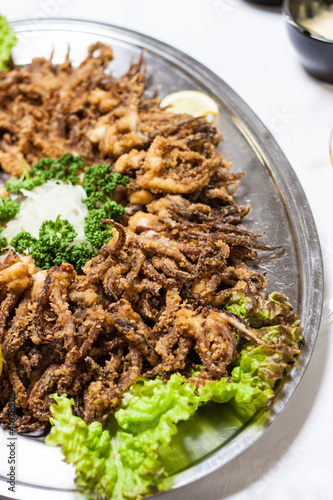 Photo: Fried octopuses and green lettuce on dinner table Fried octopuses and green lettuce on dinner table