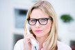 genervte frau mit brille am telefon