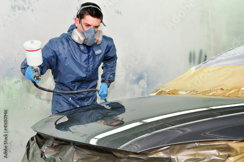 Photo: Worker painting a car. Worker painting a car.