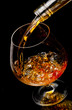 The glass with splashes cognac on black background