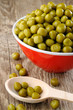 Canned peas in bowl and spoon on wooden background