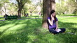 Young woman sitting in park with mobile phone, tracking shot