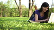 Student lying down on the grass and working on laptop