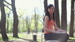 Young woman sitting in city park with laptop, tracking shot