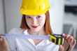 Young beautiful female with yellow helmet holding a tape measure
