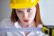 Photo: Young beautiful female with yellow helmet holding a tape measure Young beautiful female with yellow helmet holding a tape measure