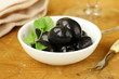 Pickle black olives in a bowl on a wooden table