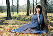 Photo: Young woman in medieval dress sitting near the tree Young woman in medieval dress sitting near the tree
